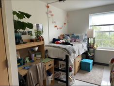 a bedroom with a bed, desk and shelves filled with stuff in it's corner