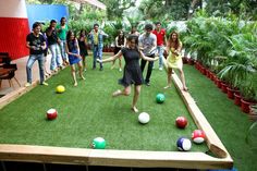 a group of people are playing with balls in an artificial space that looks like a bowling alley