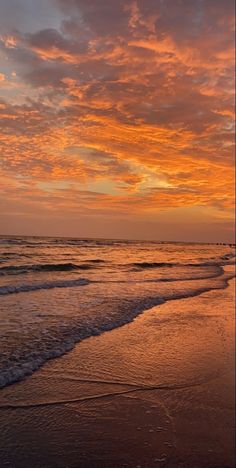 the sun is setting at the beach with waves coming in