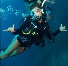 two people in scuba gear are posing for the camera while holding their hands up and pointing