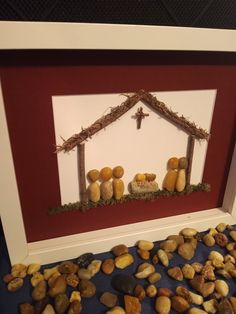 a framed nativity scene with rocks and stones in front of the mangerms