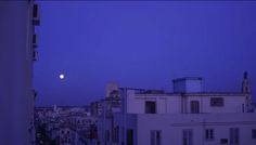 the moon is setting over some buildings in an urban area with no one around it