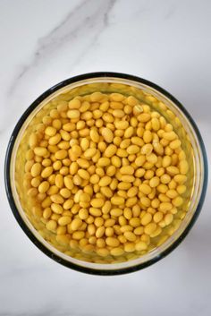 a bowl filled with yellow beans on top of a white counter