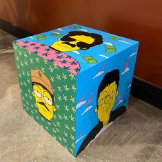 a box with the simpsons characters on it is sitting on the floor in front of a wall