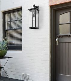 a white brick building with a potted plant next to the front door and window