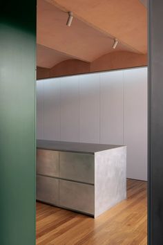 an empty kitchen with wooden floors and white cabinets