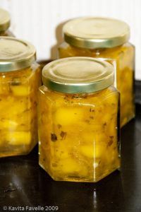 four jars filled with yellow liquid sitting on top of a black table next to each other