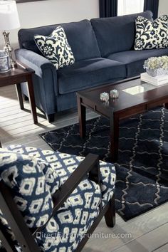 a living room with blue couches and pillows on the floor in front of a window