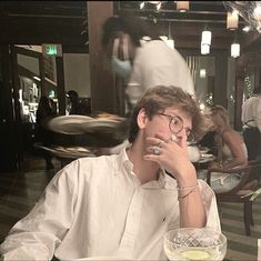 a man sitting at a table in front of a bowl of food with his hand on his face