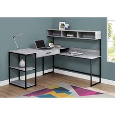 a computer desk with a laptop on it in front of a blue wall and wooden floor