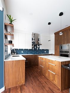 a kitchen with wooden cabinets and white counter tops next to a blue accented wall