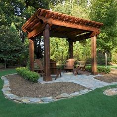 a wooden gazebo sitting on top of a lush green field