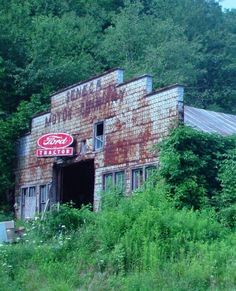 an old rusted building with a coca cola sign on it's side in the woods