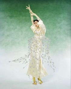 a woman in a white dress is dancing with her arms outstretched and legs spread out