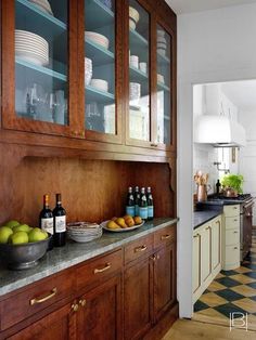 a kitchen with wooden cabinets and marble counter tops, filled with fruit on the counter