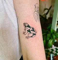 a black and white frog tattoo on the arm