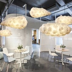 a room filled with lots of white furniture and clouds hanging from the ceiling