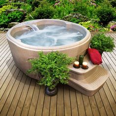 an outdoor hot tub is shown with candles on the side and plants in the back