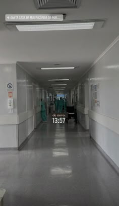 an empty hospital hallway with medical staff walking down the hall and signs on the walls