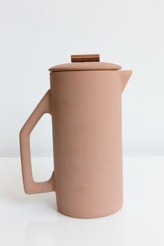 a coffee pot with a wooden handle on a white surface