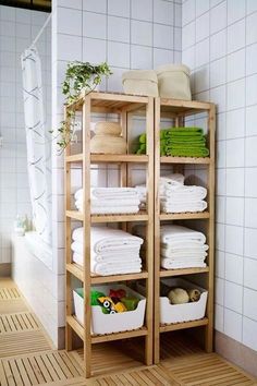 a bamboo shelf filled with lots of white towels and other household items in a bathroom