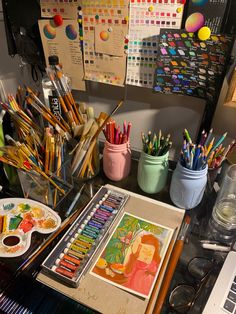 the desk is full of art supplies, such as watercolors and pencils