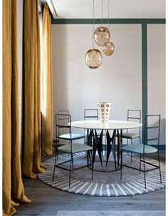 a dining room table and chairs in front of a curtained window with gold drapes