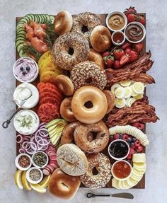 an assortment of doughnuts, fruit and dips on a platter with bacon