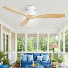 a blue couch sitting on top of a wooden floor next to a ceiling mounted fan