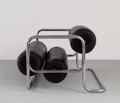 an unusual chair with four black cushions on it's back and two metal legs