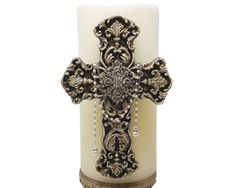 a candle with a cross on it and some beads hanging from the top of it