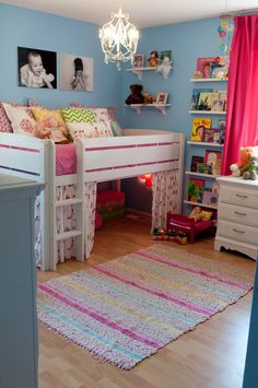 a child's bedroom with blue walls and white bunk beds, pink curtains and rugs