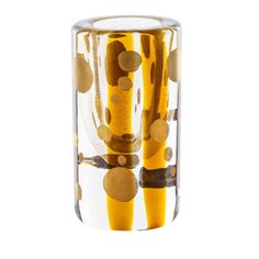 a clear glass with gold dots and circles on it's sides, in front of a white background