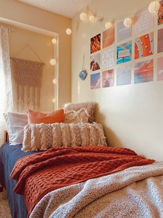 a bed with blankets and pillows in a bedroom next to a wall with pictures on it