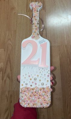 someone is holding up a birthday tag with the number twenty one on it, decorated in pink and white