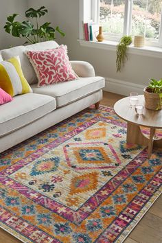 a living room with a white couch and colorful rugs on the hardwood flooring