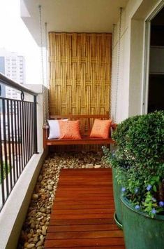 a balcony with wooden flooring and green planters on either side of the porch