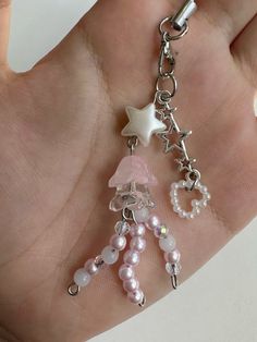 a hand holding a keychain with charms on it's side and a star hanging from the back