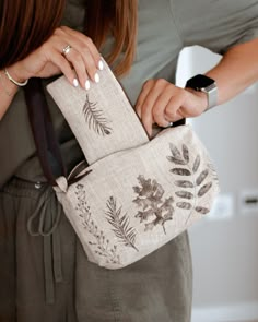 a woman is holding a bag with leaves on it and her hand in the pocket