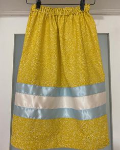 A youth sized cotton Ribbon Skirt that fits approximately a size 5-8 year old. Waist stretches to 35" / relaxed waist is  20". Length is 22". A calming yellow fabric is adorned with whimsical white vines and fixed with 1x 2" double sided satin ribbons and 1x1.5" baby blue double sided ribbon. Fully serged seams for a neat and tidy finish. Machine wash on cold gentle cycle inside out or handwash, hang to dry iron inside out on low medium heat. *Can be taken if child has smaller waist- just send a Ribbon Skirt, Ribbon Skirts, Smaller Waist, Waist Stretches, Cotton Ribbon, White Love, 5 Babies, Satin Ribbons, Neat And Tidy