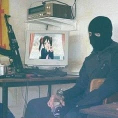 a person wearing a black mask sitting in front of a tv