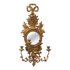 an ornately decorated wall mirror with candles on it's sides and a candle holder in the middle