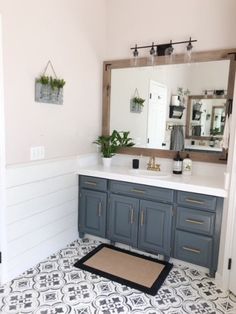 a bathroom with a large mirror and blue cabinetry on the wall, along with black and white tile flooring