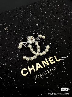 a chanel brooch is laying on top of a black cloth with stars and sparkles