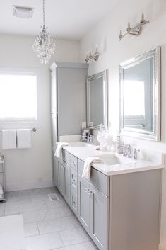 a white bathroom with two sinks and mirrors