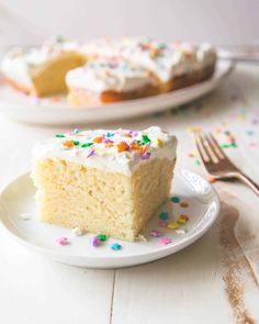 a slice of cake with white frosting and sprinkles on a plate