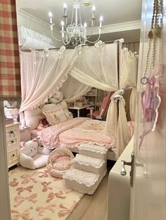 a white canopy bed sitting in a bedroom next to a chandelier and dresser