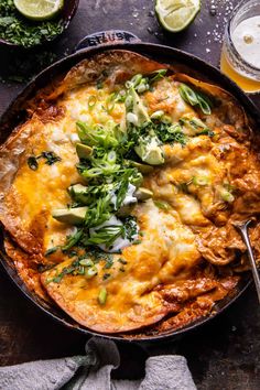 an enchilada in a cast iron skillet with limes and cilantro