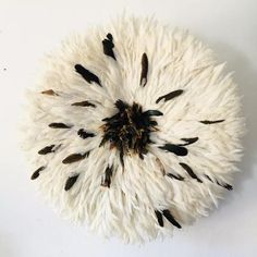 a white and black clock with feathers on it's face in the shape of a flower