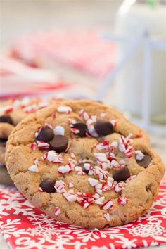 two chocolate chip cookies with candy canes on a red and white napkin